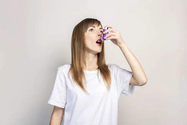 年轻妇女手里拿着吸入器 在浅色的背景上喷雾剂 班纳更容易呼吸 治疗哮喘 气管的概念 — 图库照片