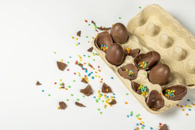 Kırık Paskalya çikolatalı tepsi ve açık arkaplanda çok renkli şeker süslemeleri. Paskalya konsepti, paskalya hediyeleri, tavşancık. Pankart.