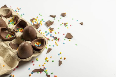 Kırık Paskalya çikolatalı tepsi ve açık arkaplanda çok renkli şeker süslemeleri. Paskalya konsepti, paskalya hediyeleri, tavşancık. Pankart.