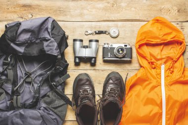 İz sürme botları, dürbünler, tahta arka planda yürüyüş aksesuarları. Yürüyüş, turizm, kamp, dağlar, orman konsepti. Pankart. Düz yatış, üst görünüm.