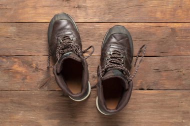 Ahşap bir arka planda yürüyüş botları. Yürüyüş, turizm, kamp, dağlar, orman konsepti. Pankart. Düz yatış, üst görünüm.