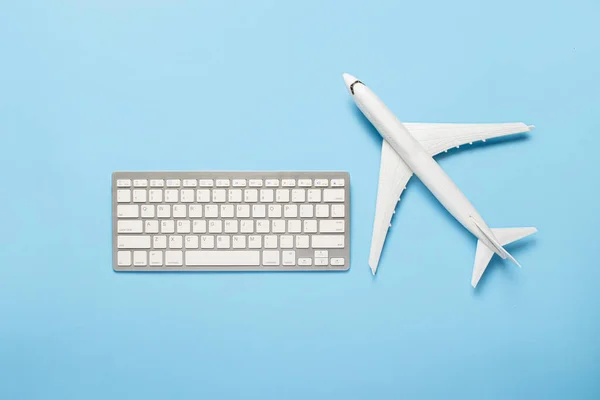 Keyboard and airplane on a blue background. Concept of travel planning, buying airline tickets online, selling air tickets. Banner. Flat lay, top view.