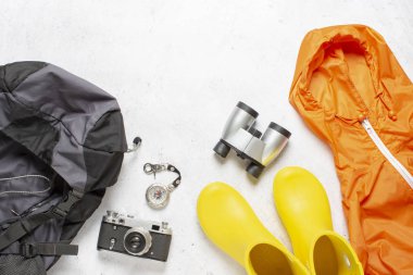 Seyahat çantası, pusula, lastik bot, ceket, kamera ve beyaz arka planda dürbün. Yürüyüş, turizm, kamp, dağlar, orman konsepti. Pankart. Düz yatış, üst görünüm.
