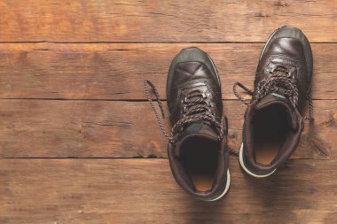 Ahşap bir arka planda yürüyüş botları. Yürüyüş, turizm, kamp, dağlar, orman konsepti. Pankart. Düz yatış, üst görünüm.