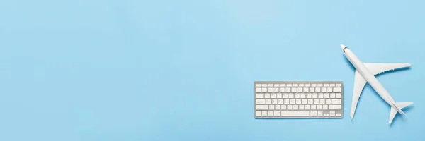 Keyboard and airplane on a blue background. Concept of travel planning, buying airline tickets online, selling air tickets. Banner. Flat lay, top view.