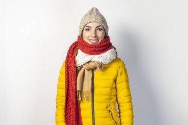 Sarı ceketli, arka planda birkaç eşarp takmış genç bir kız. Soğuk algınlığı, moda, alışveriş kavramı.