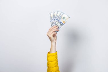Sarı ceketli bir kadın arka planda para tutuyor. Zenginlik, zenginlik, satın alma, ödeme, vergi.
