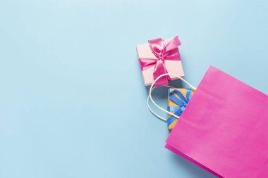 Pembe çanta ve mavi arka planda kutular. Hediye çantası ve kutular. Tatil, alışveriş, indirim kavramı. Pankart. Üst manzara, düz uzanma.