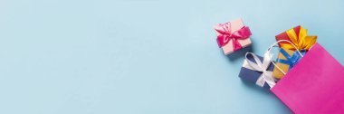 Pembe bir çanta kutusundan mavi bir arka plana düştü. Hediye çantası ve kutular. Tatil, alışveriş, indirim kavramı. Pankart. Üst manzara, düz uzanma.