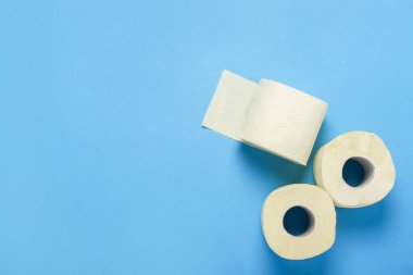 Tuvalet kağıdı mavi arka planda yuvarlanıyor. Düz yerde, üst tarafta. Hijyen konsepti, eksiklik, karantina.