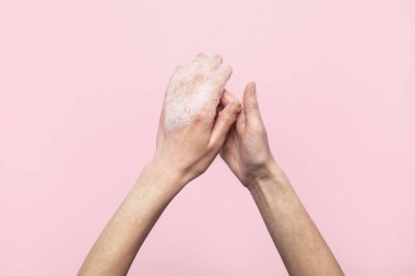 El yıkama. Pembe arka planda sabunlu kadın elleri. Yıkanma ve el ele tutuşmanın kuralları. Üst manzara, düz uzanma.