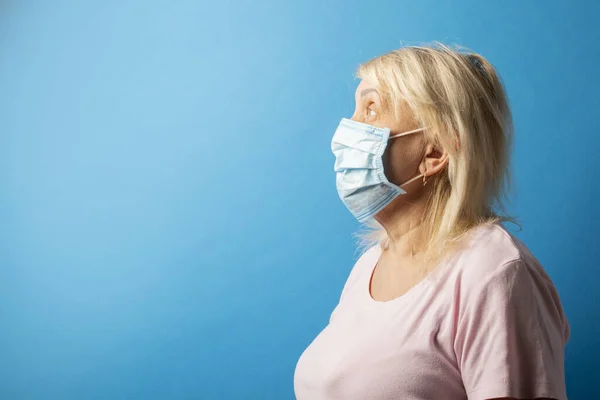 Gammal Kvinna Skyddande Medicinsk Mask Ser Bort Blå Isolerad Bakgrund — Stockfoto