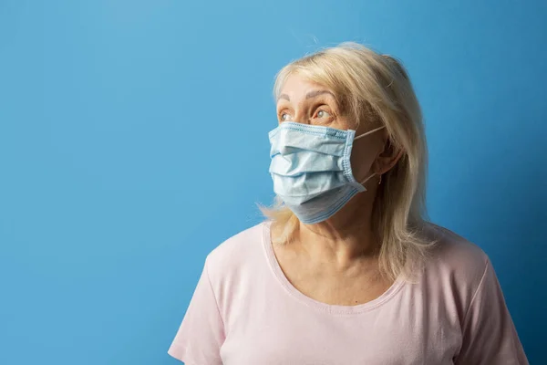 Staruszka Ochronnej Masce Medycznej Odwróciła Głowę Niebieskie Odizolowane Tło Koncepcja — Zdjęcie stockowe
