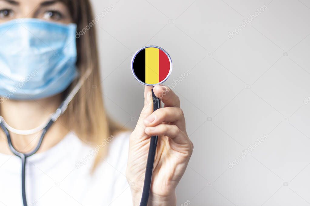female doctor holding a stethoscope on a light background. Added flag of Belgium. Concept medicine, level of medicine, virus, epidemic.