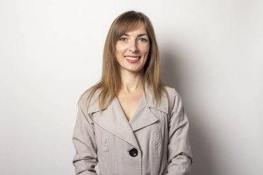 Bej bir pelerin giymiş ve arka planda poz veren gülümseyen genç kadınlar. Kavram tarzı, kadın modası.