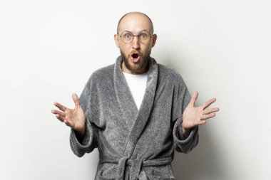 Sabahlık takmış sakallı ve gözlüklü, aydınlık bir arkaplanda şaşırmış yüzü olan kel bir gencin portresi. Duygusal bir yüz. Şaşırtıcı bir jest..