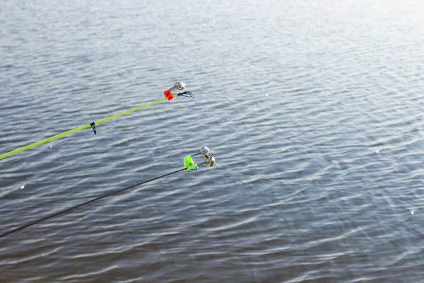 A fishing rod with a bell for fishing against the background of a river or pond on a sunny day. Concept fishing, camping, hiking.