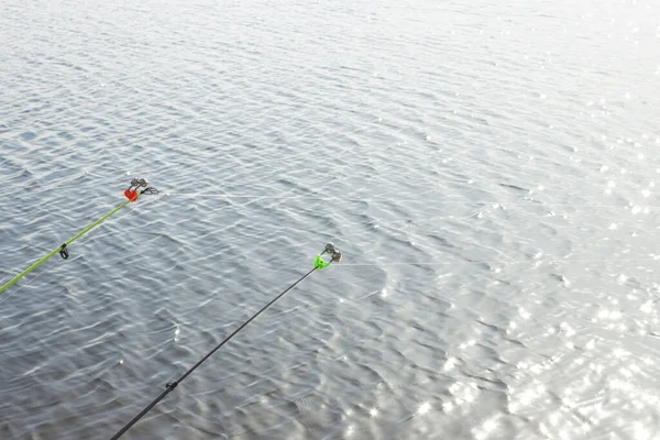 A fishing rod with a bell for fishing against the background of a river or pond on a sunny day. Concept fishing, camping, hiking.