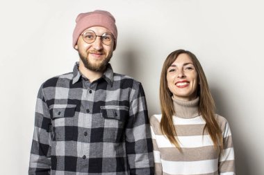 Şapkalı, ekose gömlekli, sakallı genç bir adam ve izole bir arka planda süveter giyen bir kız. Duygusal bir yüz. Mutlu çift buluşması.
