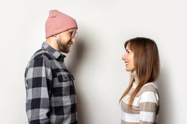 Şapkalı, ekose gömlekli, sakallı genç bir adam ve izole bir arka planda birbirine bakan süveterli bir kız. Duygusal bir yüz. Mutlu çift buluşması.