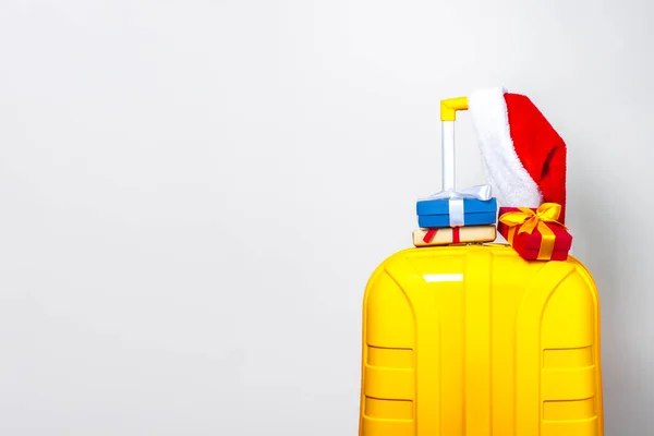 Żółtej Plastikowej Walizce Prezenty Noszenie Czerwonego Kapelusza Świętego Mikołaja Jasnym — Zdjęcie stockowe