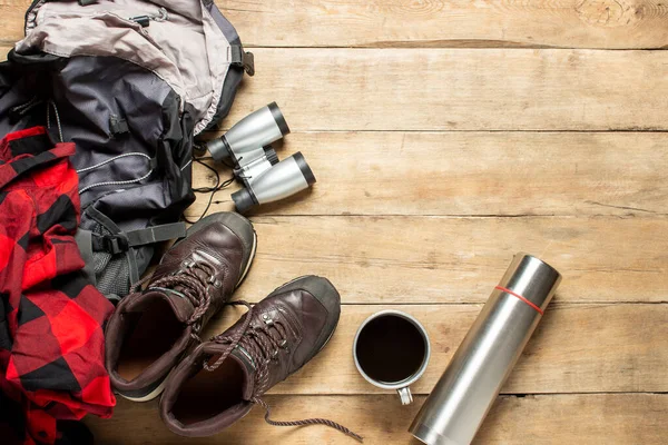 Wandelschoenen Verrekijker Shirt Thermoskan Rugzak Een Houten Achtergrond Het Concept — Stockfoto