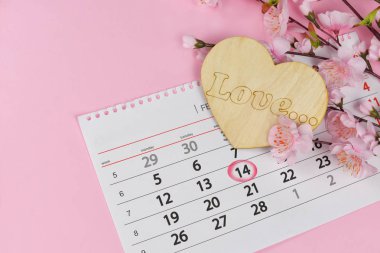 güzel bir Sevgililer günü için pembe bir arka plan üzerinde pembe çiçekler ahşap bir kalple tatil bir takvimle 14 Şubat