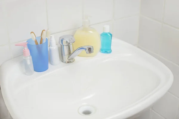 Banyo lavabosu sabunluk ve kozmetik şişeleri ile diş fırçası.