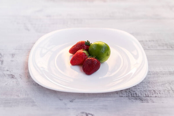 Lime and strawberry on a wooden table