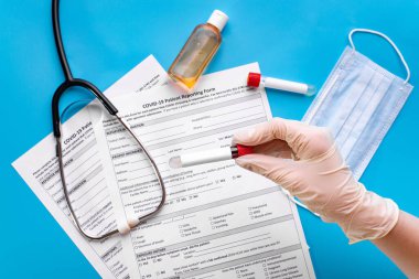 Coronavirus analizi için bir test tüpü, ince mavi tıbbi eldivenler ve koruyucu yüz maskeleri. Covid-19 virüsüne karşı korunmak için tek kullanımlık eldiven ve maskeler.