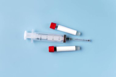 Kan analizi için iki vakum tüpü, metin yerleştirmek için boş bir etiket ve mavi arka planda bir şırınga. Coronavirüs ya da covid-19 kavramı.