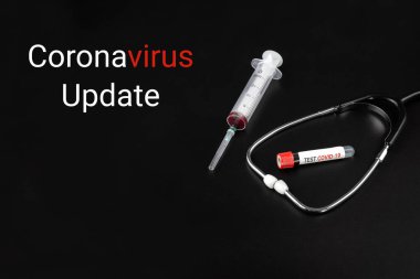 Steteskoplu COVID-19 UPDATE metni, kan örneği tüpü ve siyah arka planda bir şırınga. Coronavirüs salgını kavramı.