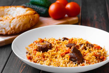 Geleneksel Özbek, İranlı, Türk, Azerbaycanlı, Hintli, kuzu etli pilav veya salatalık ve domatesli ahşap bir masada sığır eti. Doğu mutfağı kavramı..