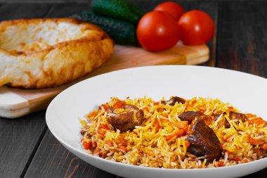 Geleneksel Özbek, İranlı, Türk, Azerbaycanlı, Hintli, kuzu etli pilav veya salatalık ve domatesli ahşap bir masada sığır eti. Doğu mutfağı kavramı..