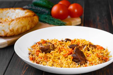 Geleneksel Özbek, İranlı, Türk, Azerbaycanlı, Hintli, kuzu etli pilav veya salatalık ve domatesli ahşap bir masada sığır eti. Doğu mutfağı kavramı..