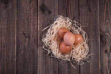 Ahşap bir arka planda saman yuvasında taze tavuk yumurtası. Uzayı kopyala Metin için boşluk