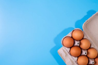 Mavi arka planda pakette çiğ tavuk yumurtası. Uzayı kopyala Mesaj için yer var. Üst Görünüm