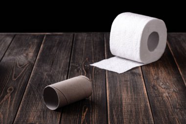 Boş bir tuvalet kağıdı rulosu ve ahşap bir arka planda izole edilmiş bir rulo.