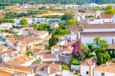 Obidos, Portekiz: Ortaçağ evleri, duvar ve Albarra kulesi bulunan şehir manzarası. Obidos hala kale duvarları arasında bulunan ve turistler arasında çok popüler bir ortaçağ kasabasıdır..