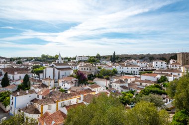 Obidos, Portekiz: Ortaçağ evleri, duvar ve Albarra kulesi bulunan şehir manzarası. Obidos hala kale duvarları arasında bulunan ve turistler arasında çok popüler bir ortaçağ kasabasıdır..