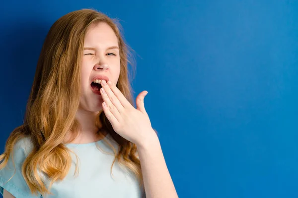 Fille sur un fond bleu bâillements — Photo