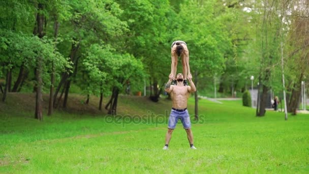 Ένας άντρας και ένα κορίτσι κάνουν σπορ, εναέρια γυμναστική στο πάρκο — Αρχείο Βίντεο