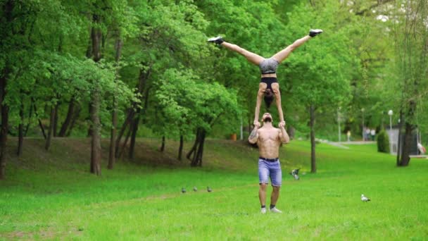Парень и девушка занимаются спортом, воздушной гимнастикой в парке — стоковое видео