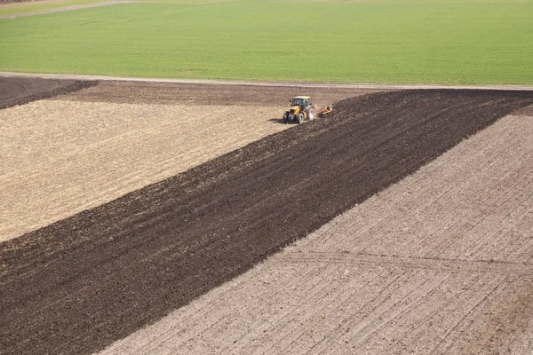 Tractor arada un campo en la primavera acompañado de torres —  Fotos de Stock