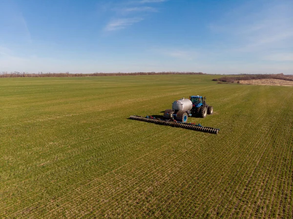 Трактор наносит жидкие минеральные удобрения на почву на озимую пшеницу — стоковое фото