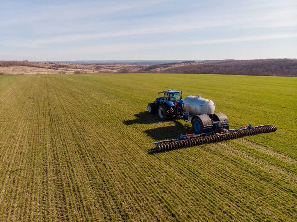 Traktor menerapkan pupuk mineral cair ke tanah pada gandum musim dingin — Stok Foto