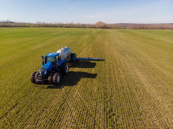 Trator aplicando fertilizantes minerais líquidos no solo no trigo de inverno — Fotografia de Stock