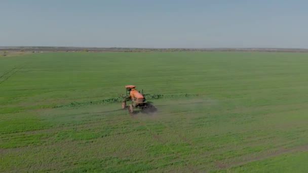 殺虫剤を噴霧するためのヒンジシステムを持つトラクター。トラクターとの肥料、エアロゾルの形で、冬の小麦の分野で — ストック動画