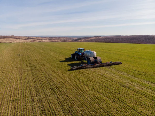 Tractor applying liquid mineral fertilizers to the soil on winter wheat