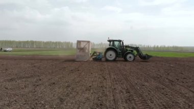 Kolza tohumu eken traktör tohumu seçim alanı baharı. Arka planda, buğday arsaları.
